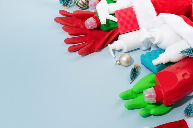 Christmas cleaning Cleaning tools and Christmas decorations top view flat lay on blue background with copy space