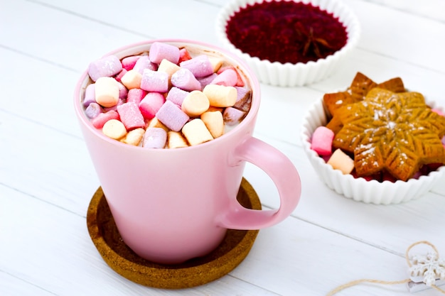 Christmas cocoa marshmallow pink cup and ginger biscuit white wooden table raspberry jam