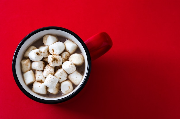 Christmas cocoa with marshmallow in mug on red.