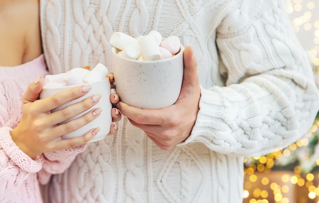 Christmas cocoa with marshmallows in the hands of a man and a woman, Selective focus.