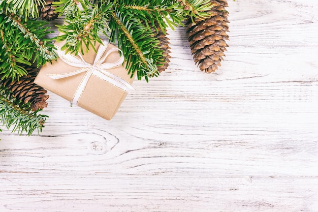 Christmas composition background Christmas gift with pine cones and fir branches on wooden background Flat lay top view copy space Toned