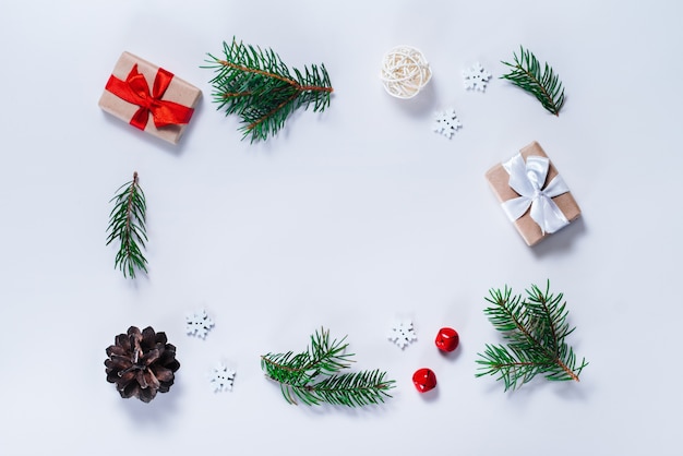 Christmas composition. Border of pine tree branches with holiday decorations on white background. Top view, flat lay.