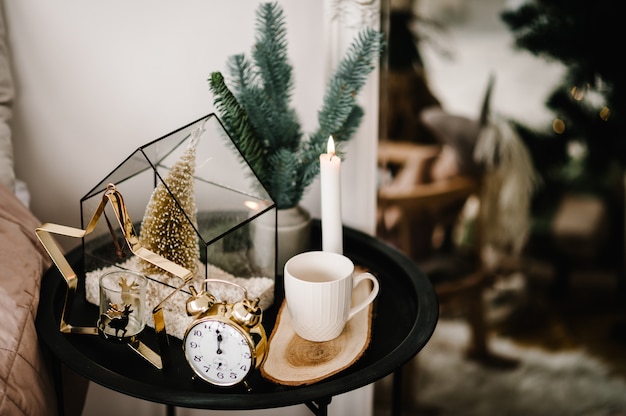 Christmas composition. Candle, cup coffee, vintage gold clock, metal gold candle holder in the shape of a star on the table. Interior and decoration at home. Close up. Christmas holiday eve.