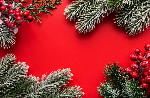 Christmas composition Christmas red decorations fir tree branches on red background Flat lay top view copy space