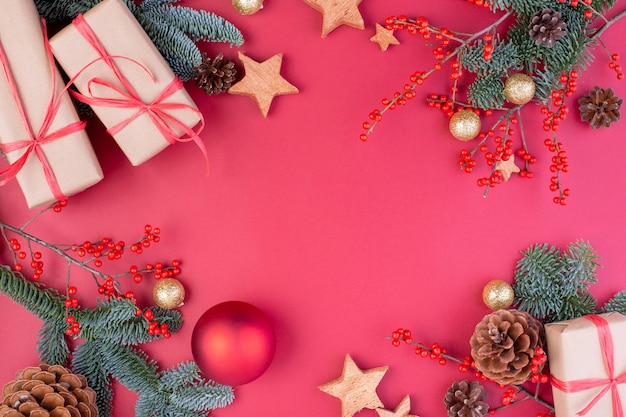 Christmas composition. Christmas red decorations, fir tree branches with toys gift boxes on red background. Flat lay, top view, copy space