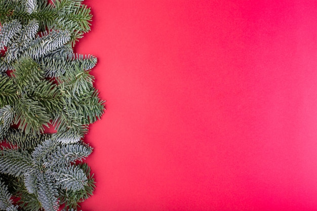 Christmas composition. Christmas red decorations, fir tree branches with toys gift boxes on red background. Flat lay, top view, copy space.