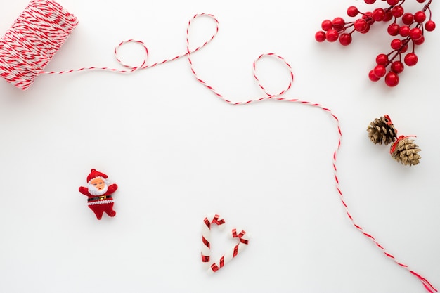 Christmas composition. Christmas Ribbon, holly berry, candy cane, santa claus, and pine cone. Creative flat lay, top view design