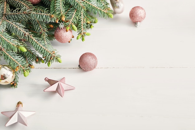 Christmas composition. Fir branches on wooden white wall Flat lay, top view, copy space. Christmas still life. Christmas frame made of fir branches and pink toys.  Happy New Year