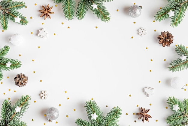 Christmas composition Frame made of fir tree festive silver decorations on white background Flat lay Minimal layout