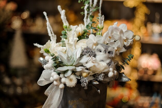 Christmas composition in the grey box of white orchids, succulent and different ornaments decorated with bow tape