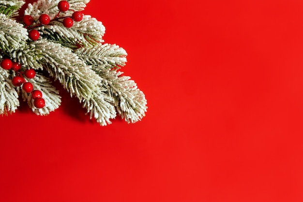 Christmas composition on red background made of snow tree and red berries. Christmas concept, flat lay, top view, copy space.