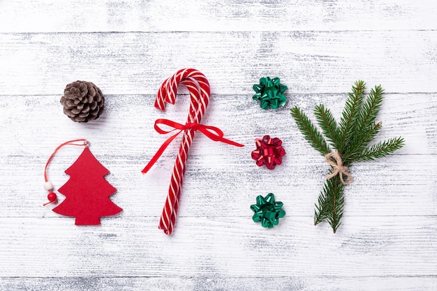 Christmas composition. Red gifts, fir tree, fir branch and cone, candy canes on wooden background. Flat lay, top view - Image