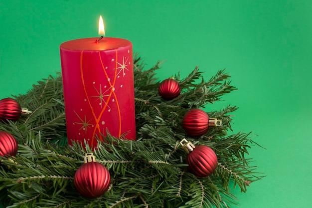 Photo christmas composition with christmas ring or wreath and red burning candle on the green background copy space closeup