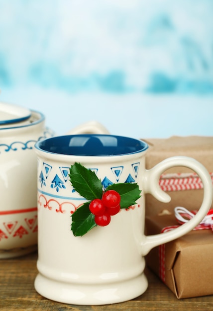 Christmas composition with cup and teapot of hot drink, on wooden table