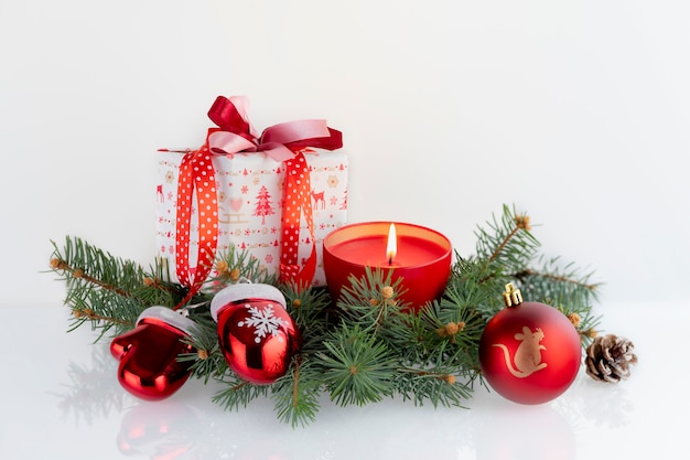 Christmas composition with decorations, gift boxes, red candle, gauntlets of Santa Claus and baubles on white . Christmas holidays  with copyspace .