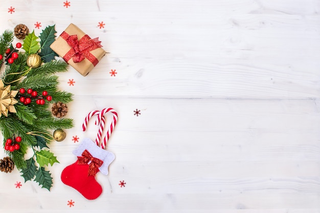 Christmas composition with fir branches, candy, gifts, pine cones and stars on light wood 