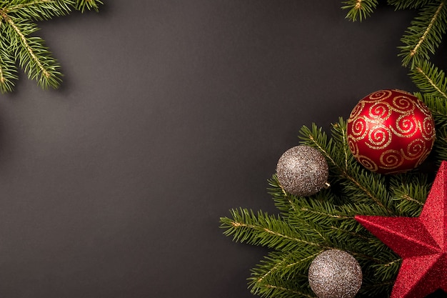 Christmas composition with fir branches, christmas ornaments and gold balls on black background