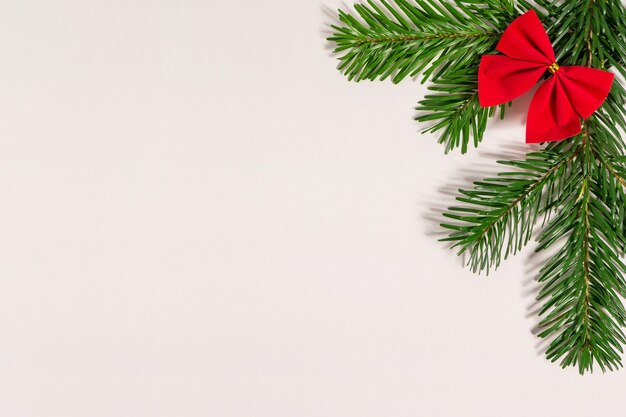 Christmas composition with fir branches and red bow on white background, flat lay, top view.