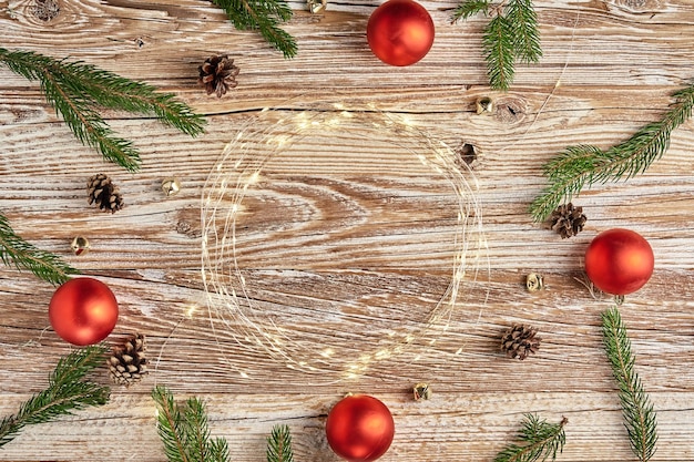 Christmas composition with fir tree branches and lighting garland on wooden background