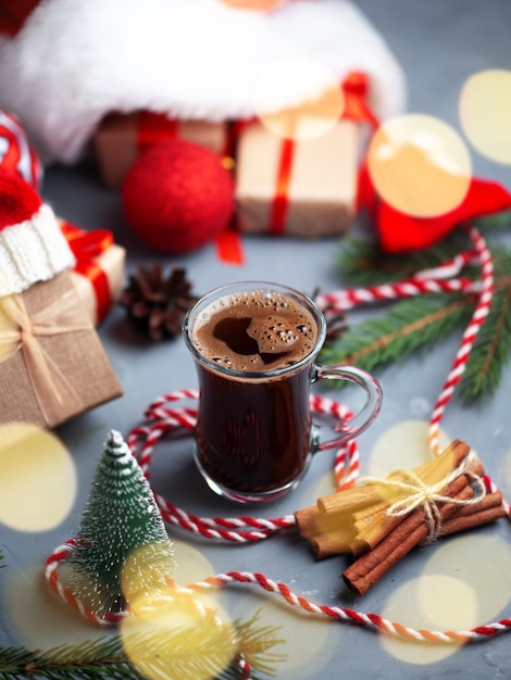 Christmas composition with gift boxes in Santa hat and a glass of coffee