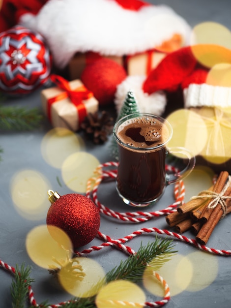 Christmas composition with gift boxes in Santa hat and a glass of coffee