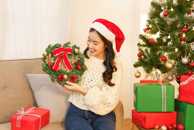 Christmas concept Asian woman holds wreath decorating with fir branches and christmas decorations