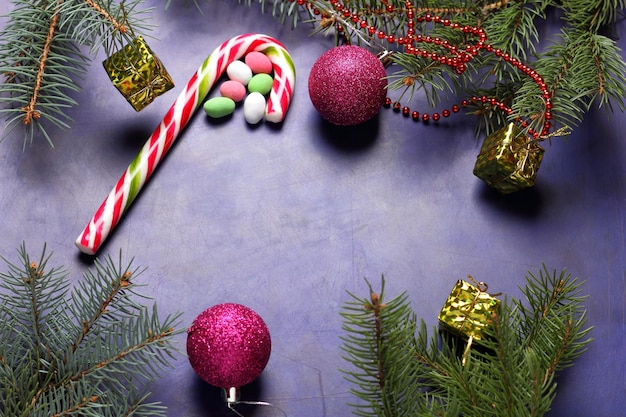 Christmas concept Christmas toys candy cane Christmas tree branches on a purple background Closeup