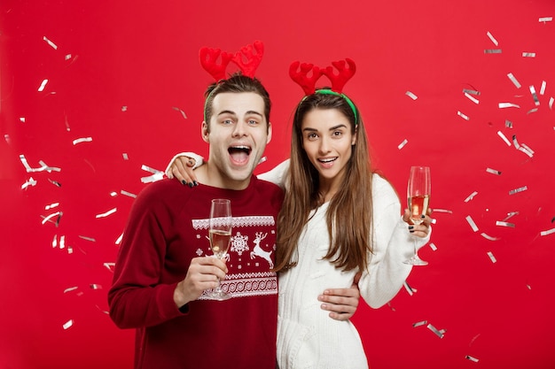 Christmas Concept Happy caucasian man and woman in reindeer hats celebrating christmas toasting with champagne flutes congratulating on xmas