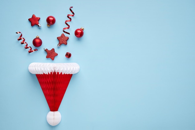 Christmas concept. Paper santa claus hat on a blue background with festive attributes. Top view.