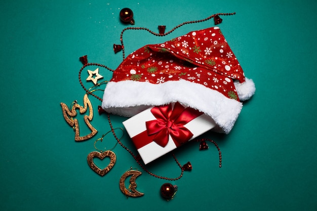 Christmas concept. Top view of  gift box with red bow near Santa hat and tree toys,