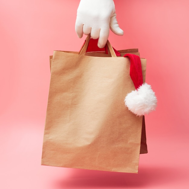 Christmas concept, two paper bags in hand, discounts on clothes and accessories, on pink background