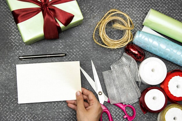 Christmas concept with gift box clews of rope papers rolls and colorful ribbons and scissor and h