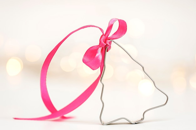 Christmas cookie cutter with gift ribbon and blurry lights on the background