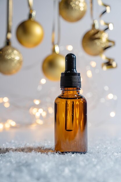 Christmas cosmetics Pipette dropper bottle with beauty face oil on a sparkling golden baubles background Face and body treatment gift concept