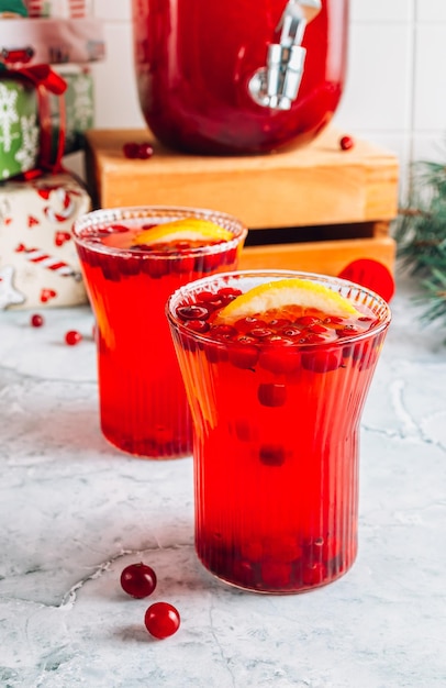 Christmas cranberry punch with oranges in a pitcher and glasses on gray marble table