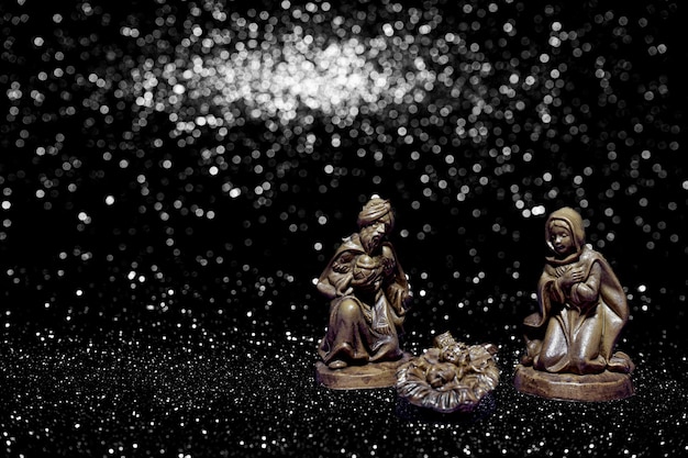 Christmas crib on stars background with space for text. Dark background.