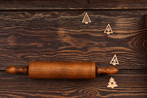 Christmas culinary layout on a wooden background. Wooden rolling pin with Christmas-tree elements for the menu of the festive table. Top view, flat style.