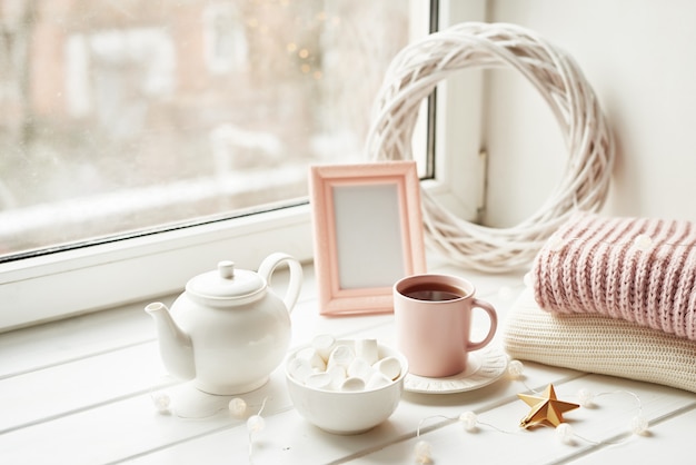 Christmas decor, balls, woolen plaid on the window , home comfort concept, seasonal winter celebrations. Christmas pink cup with marshmallow.