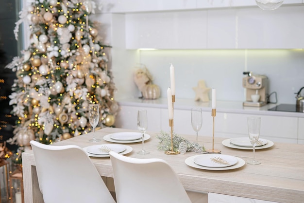 Christmas decor. Bright interior of white kitchen with decorated Christmas tree, garlands