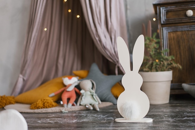 Christmas decor for the children's room homemade plywood bunnies with soft tails on the background of children's toys Copy space