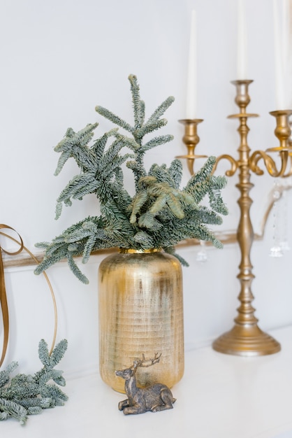 Christmas decor in a classic living room or Spruce branches in gold vases with toys and a gold candlestick