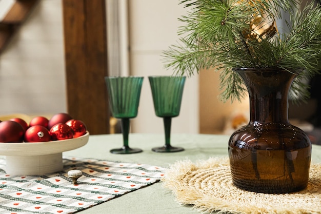 Christmas decor on the table Vase with fir branches and glasses with lights on the background