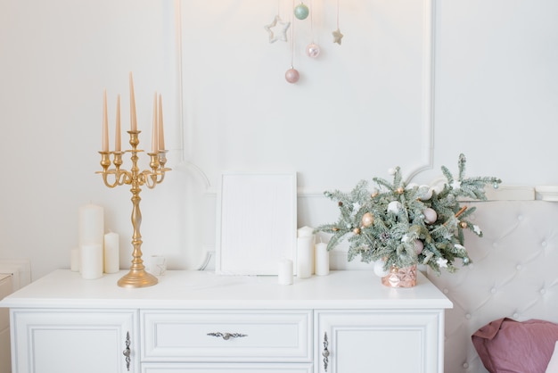 Christmas decor white chest of drawers in the bedroom or living room, candlestick, spruce arrangement and candles