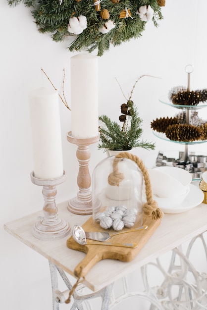 Christmas decor on a white table. Candles, silver walnuts on a chopping Board