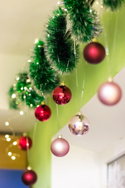 Christmas decor above the window Green garland and balls of red and pink color