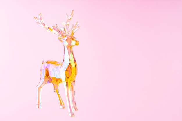 Christmas decoration deer figurine on a pink background. Christmas composition with holographic toy deer. Festive holiday concept. Copy space