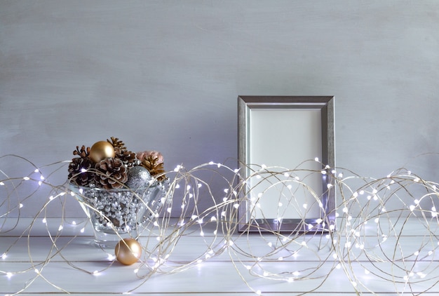 Christmas decoration mock up in a frame with cones christmas lights on a white table copy space