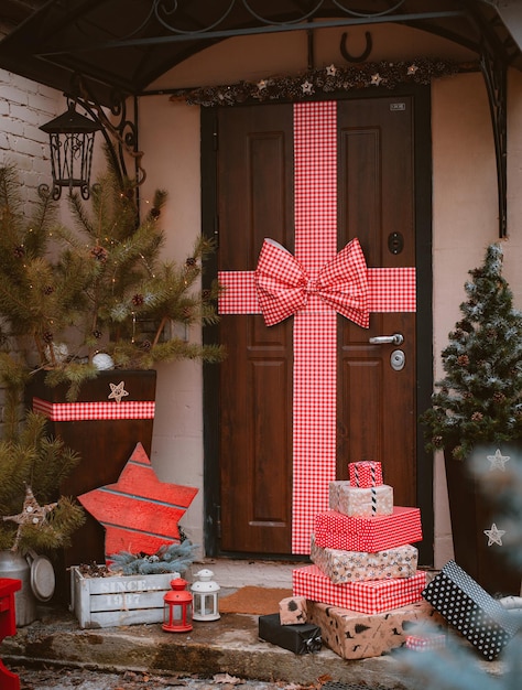 Christmas decoration of the porch of the house. The entrance door is decorated with a large red tied bow. New Year, Xmas, festive atmosphere handmade