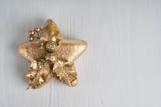 Christmas decoration in shape of golden star on white wooden background