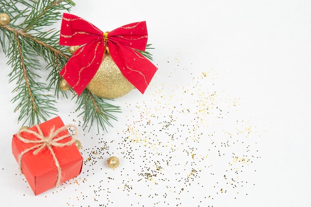 Christmas decoration, shiny yellow ball with red bow on Christmas tree branch and red gift box isolated on white background